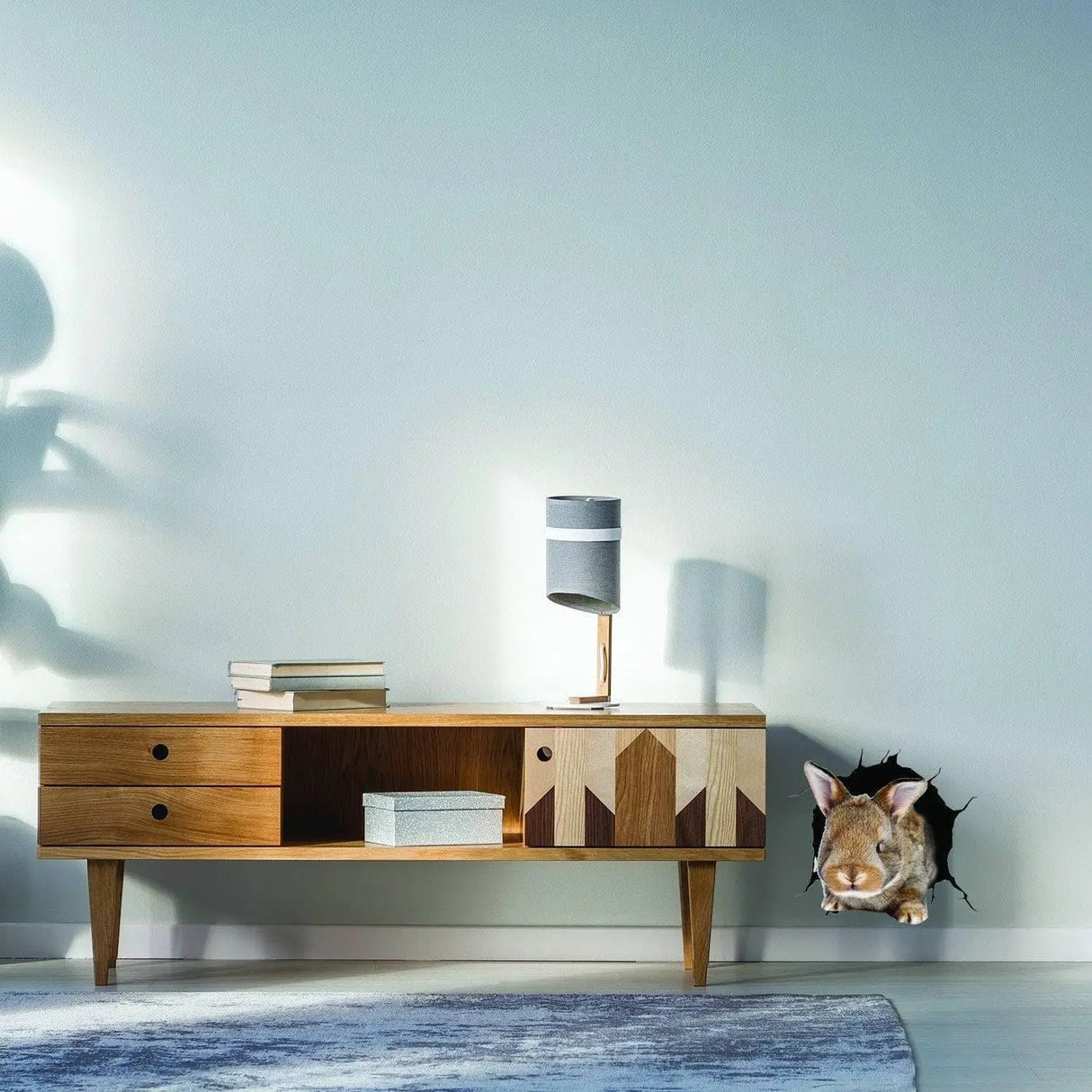 3D rabbit wall sticker popping out of wall above a modern wooden sideboard in a stylish room interior.