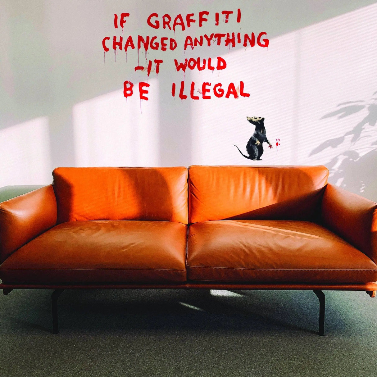 Artistic urban style vinyl wall decal featuring graffiti-style text and a rat on a wall next to a cozy orange couch.