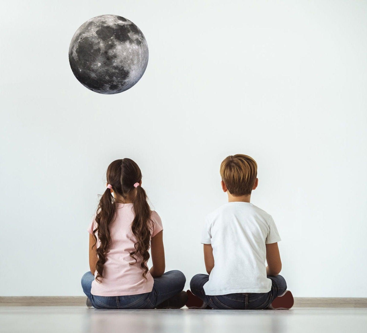 Children admiring a realistic moon wall decal, creating a magical atmosphere in a room.