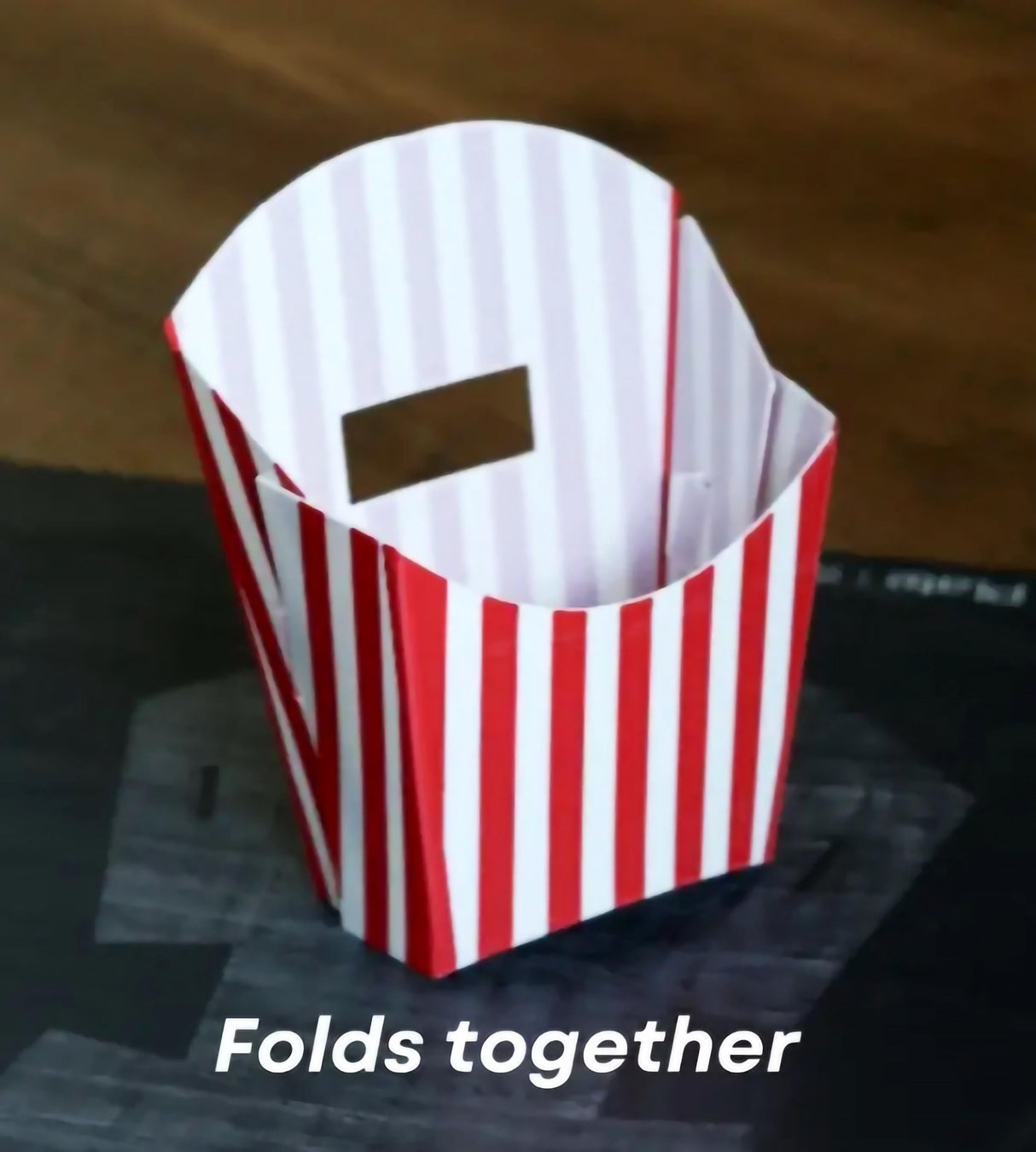 Origami-style red and white striped container folds together.