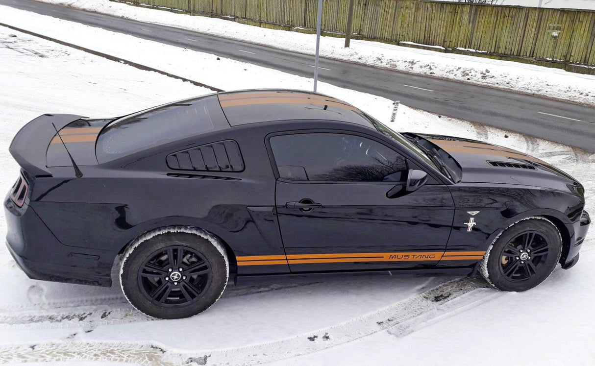 Автомобиль Mustang с гоночными полосами на заснеженной дороге.