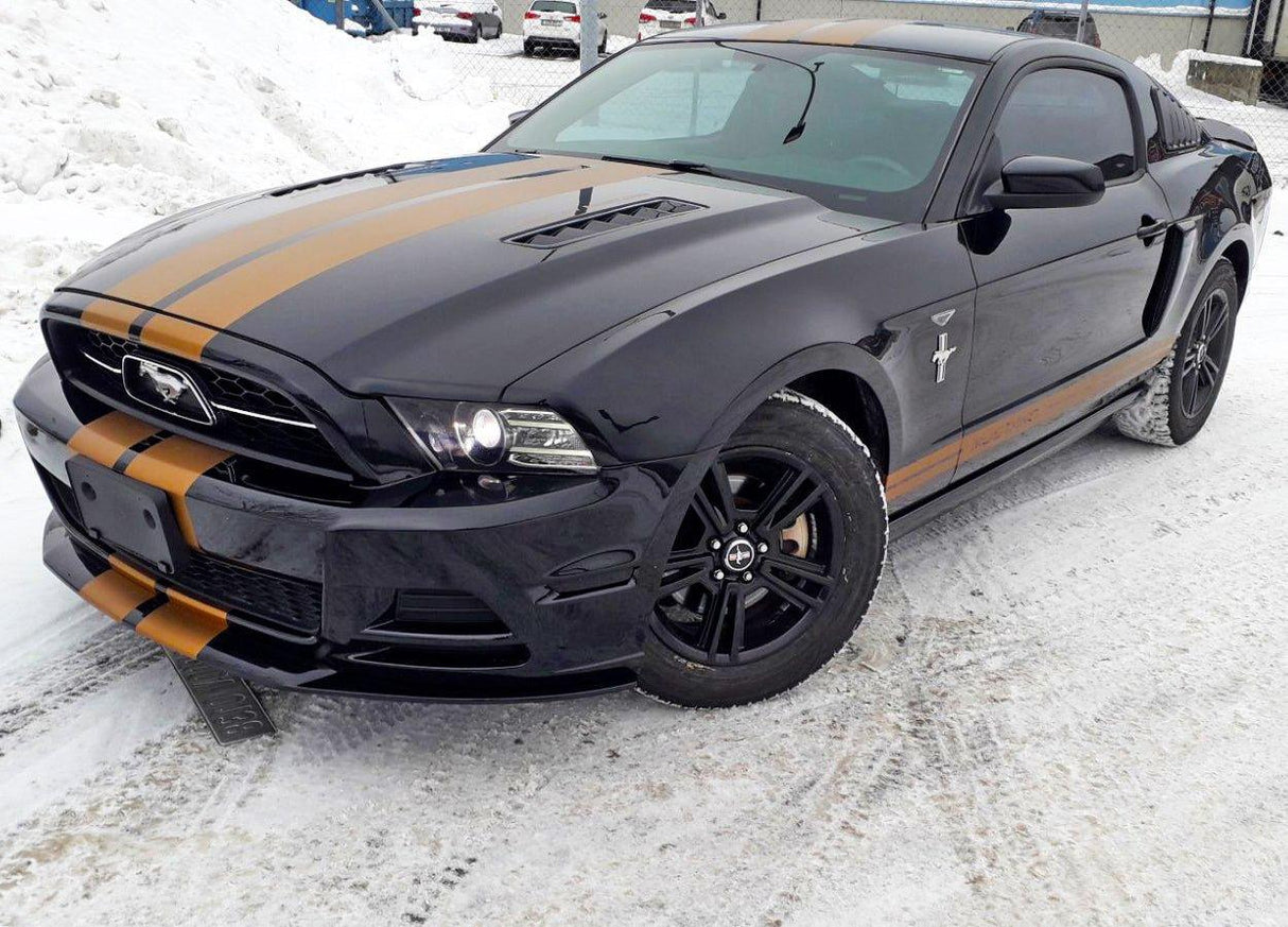 Stylish black car with gold racing stripes, showcasing two lines racing decals on snowy surface.