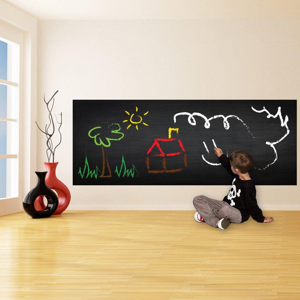 Child drawing on a black chalkboard wall sticker, showcasing creativity in a bright kitchen space.