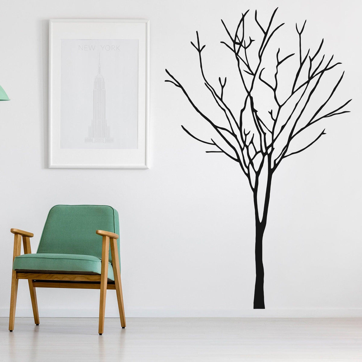 Black tree wall decal in a modern room with green chair and art.