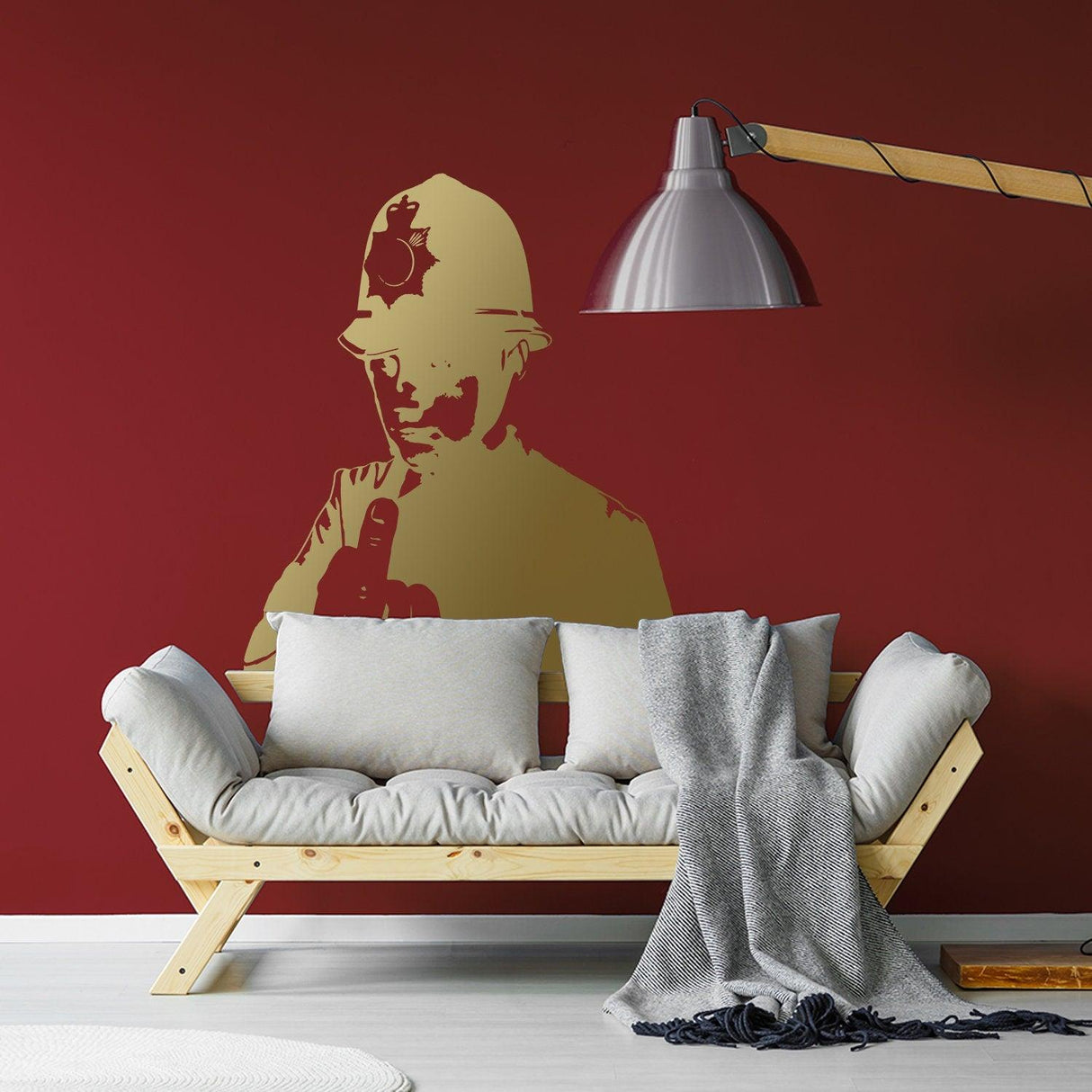 Gold policeman middle-finger wall decal displayed above a sofa on a red wall.