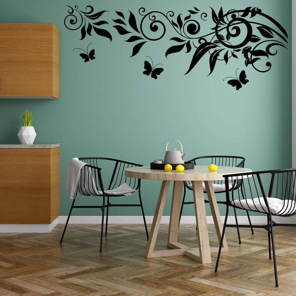 Black butterfly vinyl wall decals over a teal kitchen wall with a wooden table and black chairs.
