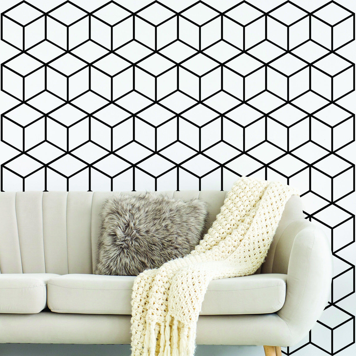 Geometric black and white hexagon honeycomb wall mural in modern living room with cozy sofa and decorative throw.