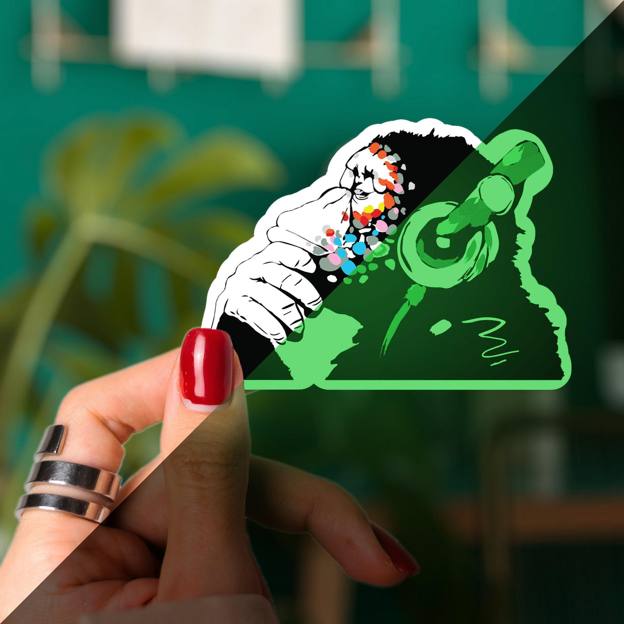 Glow in the dark monkey vinyl sticker held in hand, featuring playful design with headphones and vibrant colors.