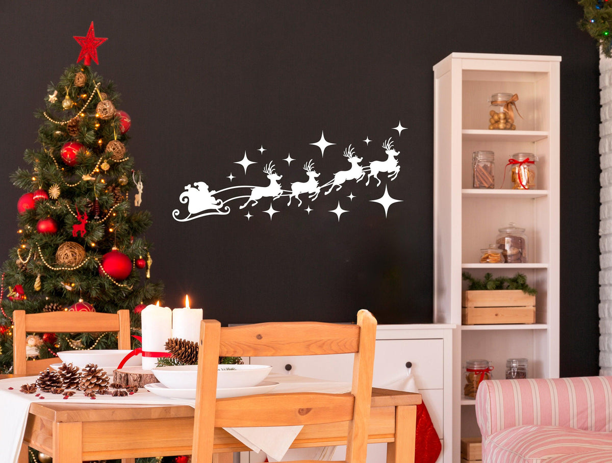 Santa sleigh and reindeer silhouette decal above a festive Christmas tree in a cozy dining area.