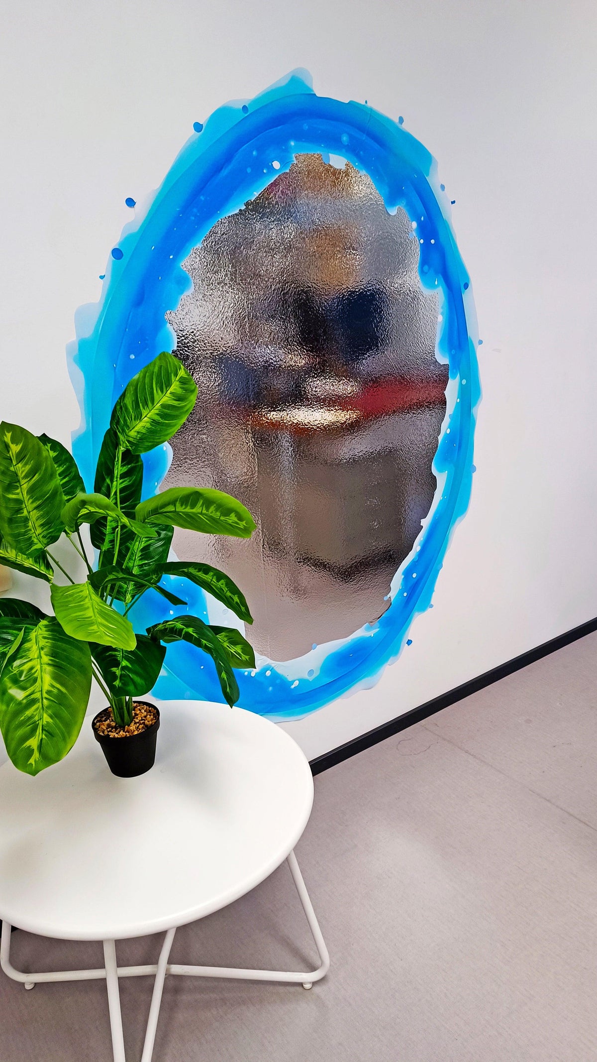 Blue and orange portal aura wall sticker on a white wall, with a decorative plant and table.