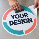 Example of custom floor sticker application showing flexible printed vinyl, backing paper and a squeegee