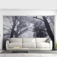 A dramatic misty forest wallpaper mural covering a living room wall with tall fog-covered trees.