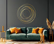 Elegant gold circle wall sticker on dark wall above a modern green sofa with orange cushions, enhancing contemporary decor.