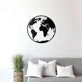 Minimalist black globe wall decal on white wall above a gray couch with decorative pillows and a potted plant.