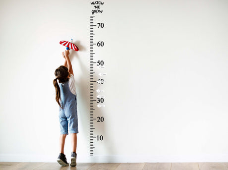 Child measuring height on a wall growth chart decal, stylish way to track growth milestones up to 70 inches.