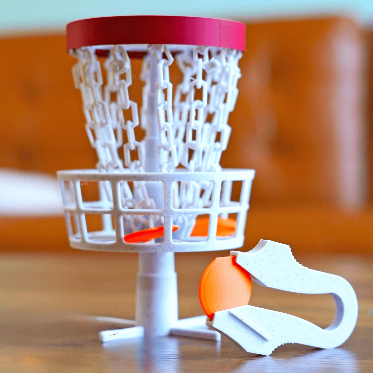 Mini disc golf basket with chains and an orange disc.