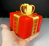 3D printed Annoying Gift Box with red and gold design, held in hand.