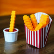 Colorful 3D-printed French fry clips in a fun striped container.