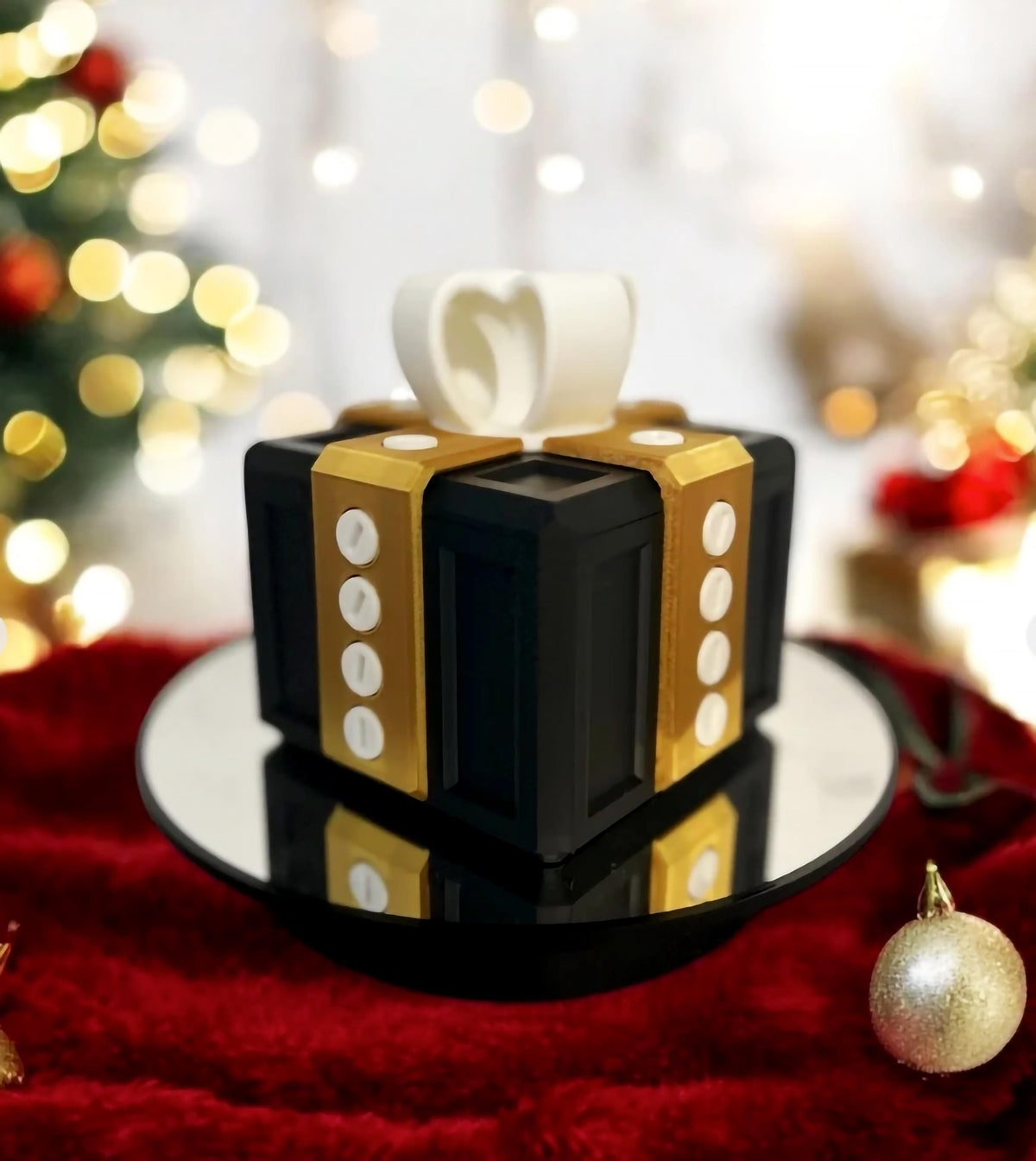 3D-printed Annoying Gift Box in black and gold design on a reflective surface.