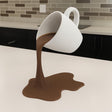 3D printed floating coffee cup sculpture with a suspended pouring stream and spill-shaped base.