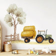 A watercolor-style wall decal in a nursery showing a green tractor pulling a hay-loaded trailer.