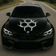 Black sports car with a large white honeycomb geometric decal centered on the hood.