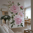 A bright, elegant living space with a large wall mural featuring soft pink watercolor peonies and green leaves.
