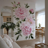 A bright, elegant living space with a large wall mural featuring soft pink watercolor peonies and green leaves.
