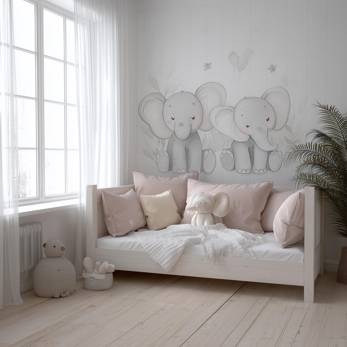 A soft-toned nursery with two hand-drawn baby elephant decals on the wall above a daybed, styled with blush pink pillows.