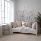 A soft-toned nursery with two hand-drawn baby elephant decals on the wall above a daybed, styled with blush pink pillows.