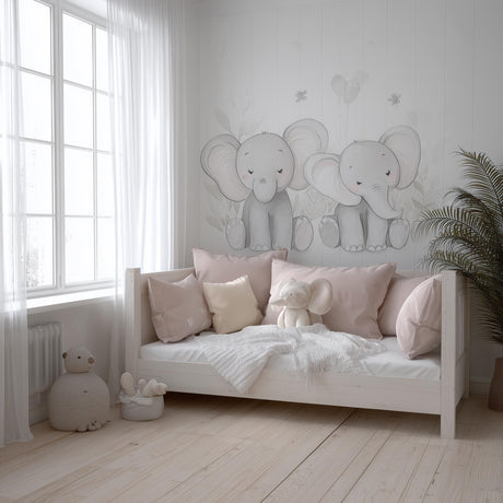 A soft-toned nursery with two hand-drawn baby elephant decals on the wall above a daybed, styled with blush pink pillows.