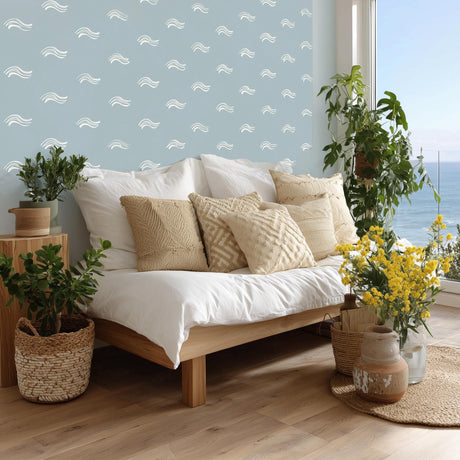 A serene coastal bedroom with white ocean wave decals scattered across a soft blue wall.