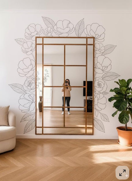Vinyl wall decals of outline flowers and leaves arranged around a large rectangular mirror in a modern living room.