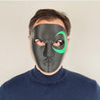 Person wearing a black 3D-printed half-face mask with a green crescent design around one eye.