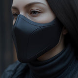 Close-up of a woman wearing a matte black 3D printed half-face mask with sleek curved lines.