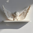 3D printed wall shelf with a minimalist praying angel figure and wide wings and matte white PLA.