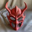 3D printed demon mask with horned gothic design made of matte PLA plastic, displayed on fabric background.