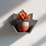 Gray 3D printed maple-leaf wall shelf holding a small potted plant.