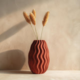 Terracotta-colored 3D printed vase with an organic wavy surface and sculptural opening.