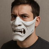 A man wearing a white 3D-printed half-face mask with a fierce, snarling expression and visible fangs.