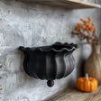 3D printed wall shelf shaped like a black witch cauldron with wavy rim and matte PLA texture.