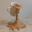 3D printed floating spilled-coffee cup sculpture with a suspended cup and splash-shaped base.