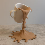 3D printed floating spilled-coffee cup sculpture with a suspended cup and splash-shaped base.