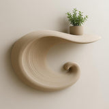 A beige 3D printed floating shelf in the shape of a curling wave.