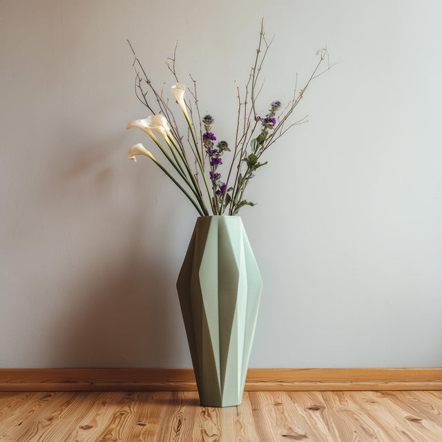 Tall faceted 3D printed vase holding dried flowers in a minimalist interior.