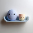 3D printed wall shelf with a rounded ledge holding a smiling egg character and a small cup character.