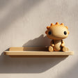 3D printed wall shelf with a small sun-like character sitting on a slim tray-style ledge.