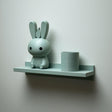 3D printed wall shelf with a slim back-edged ledge holding a rounded bunny character and a cylinder pot.