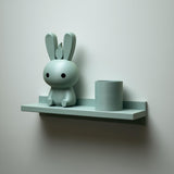 3D printed wall shelf with a slim back-edged ledge holding a rounded bunny character and a cylinder pot.