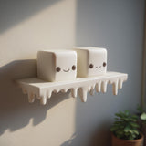 3D printed wall shelf with a dripping edge and two marshmallow-like cube characters with faces.